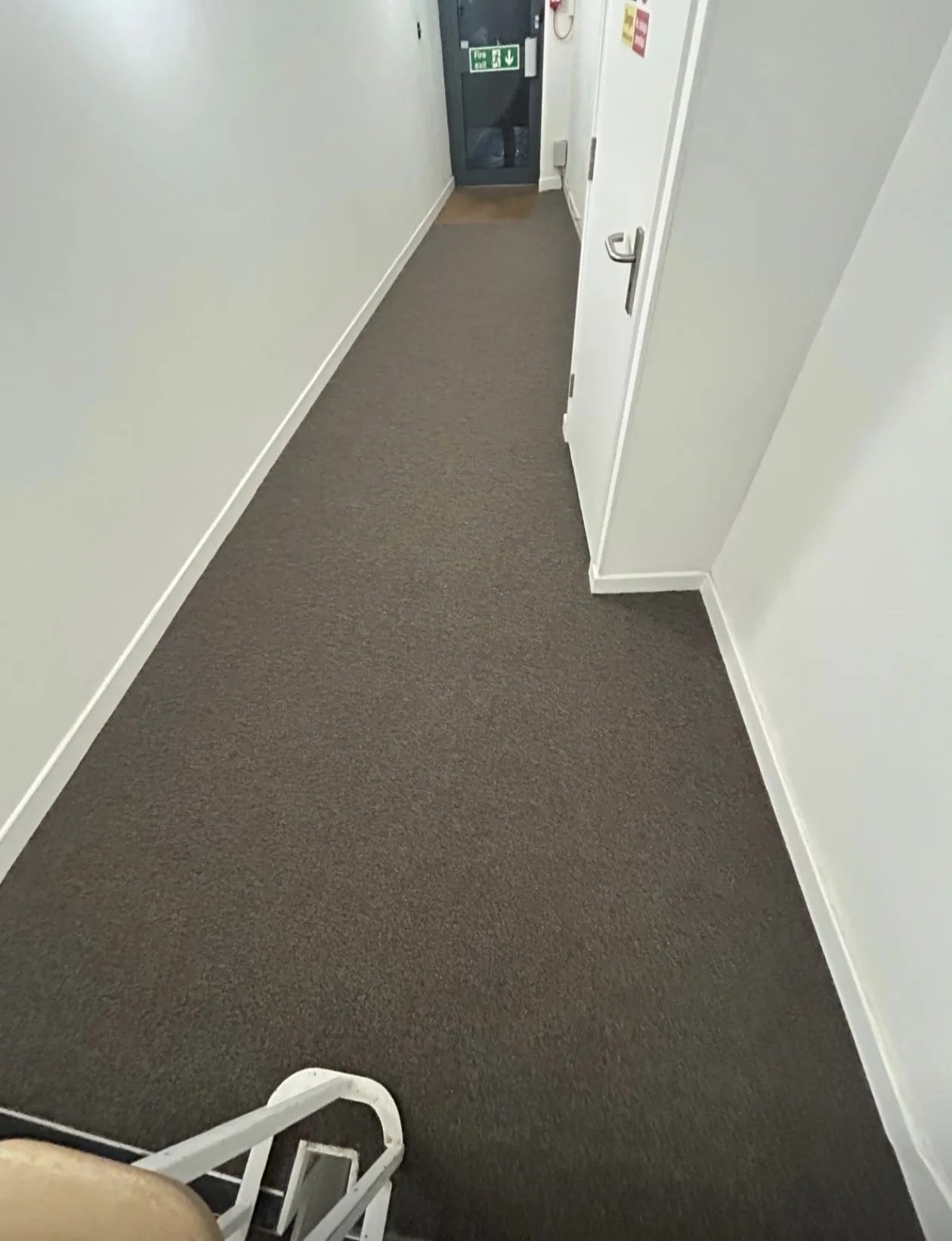 Communal corridor with dark carpet fitted wall to wall and cut in to the doorways.