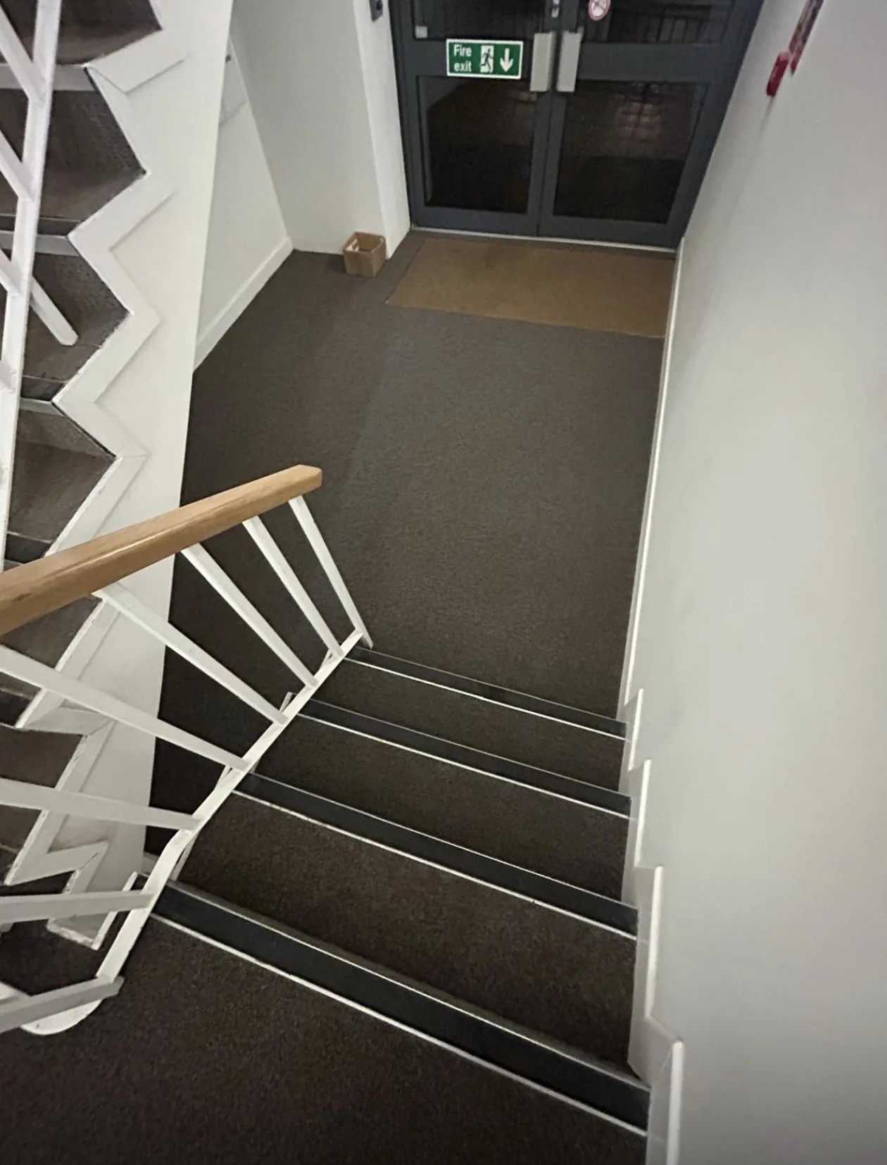 Staircase with dark carpet fitted over each tread and riser, carried through to the landing.