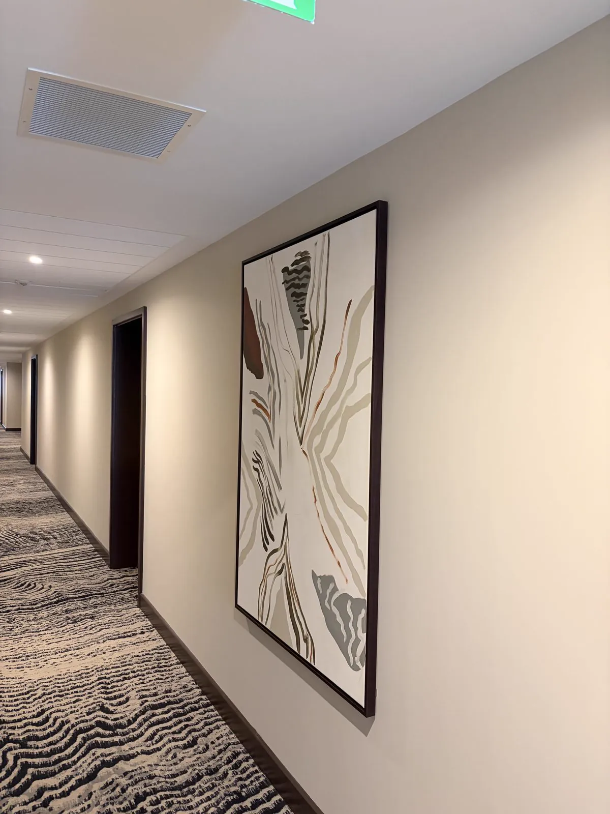 A large framed abstract print hung on a corridor wall above patterned carpet.