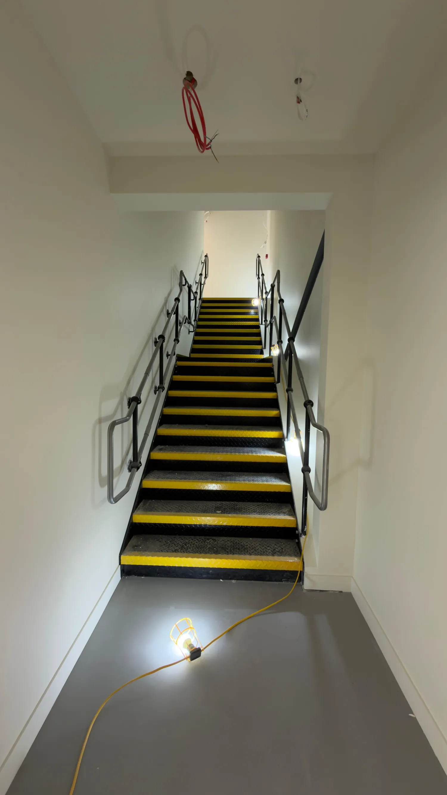 Stairwell with white walls and yellow nosings to the stair treads.
