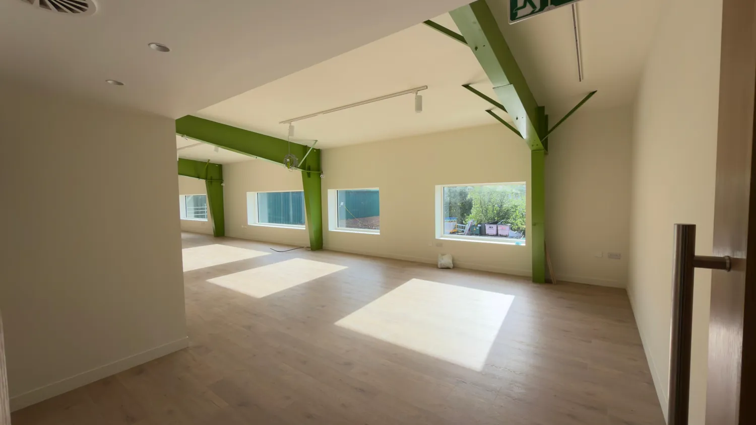 Office interior with a green structural steel portal frame against cream walls and ceiling.